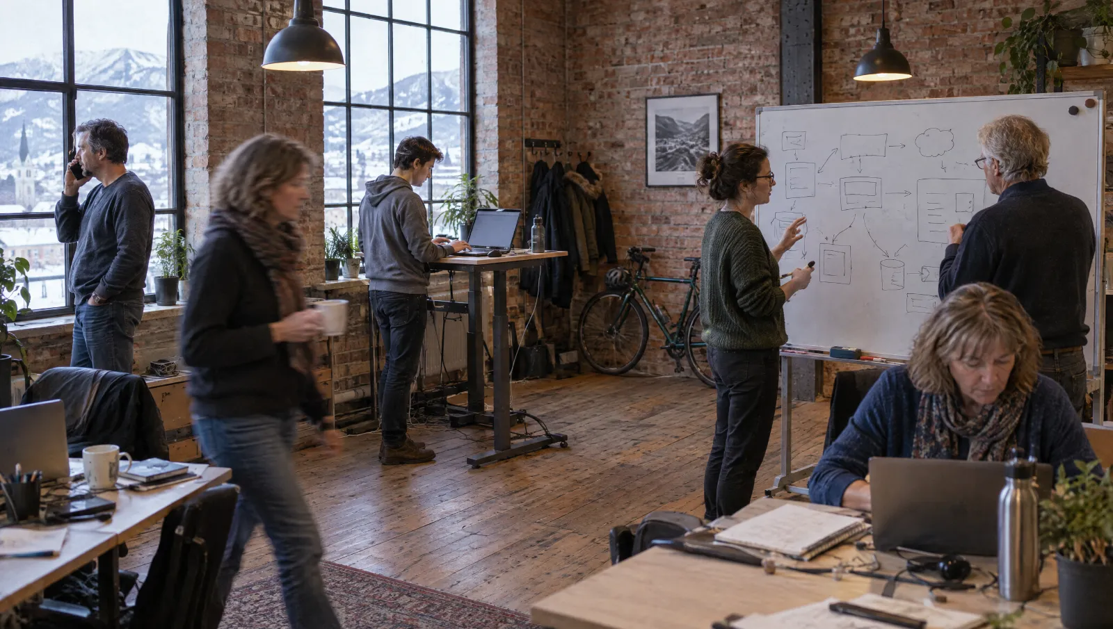 Kleines Team arbeitet in einem hellen Büro mit Blick über die Dächer einer Altstadt